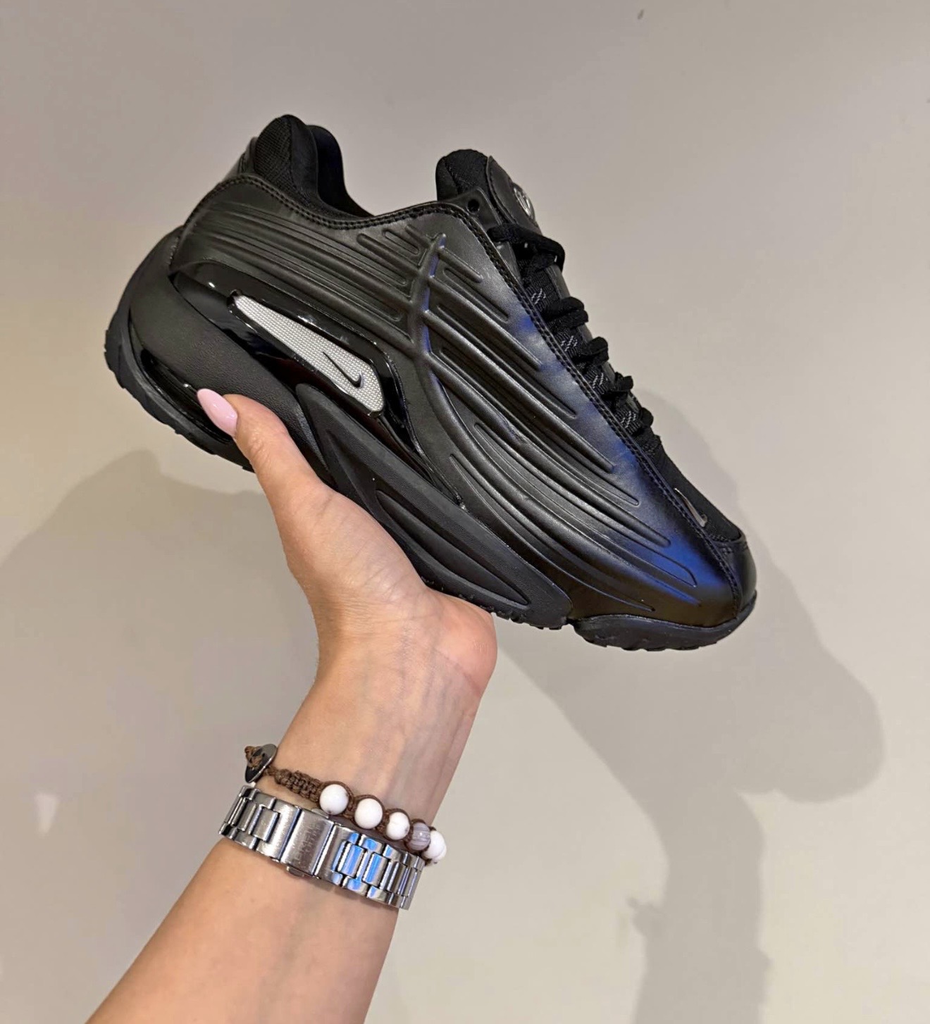 Schwarzer Nike Sneaker mit blauen Reflexen in der Hand